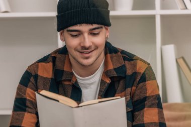 Genç adam sonbahar kış kıyafetleri içinde kitap okuyor.