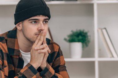 Evdeki genç adam kanepede otururken çok düşünceli.