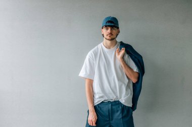 Sokak duvarında şapkası olan genç adam.