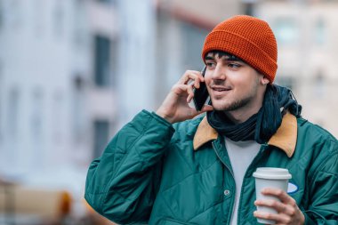 Kışın sokakta cep telefonuyla konuşan genç bir adam.