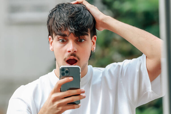 портрет молодого человека, смотрящего на мобильный телефон удивлен
