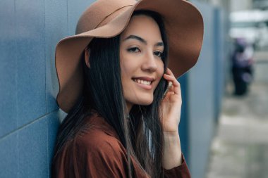 Şapkalı kız sokakta telefonla konuşuyor.