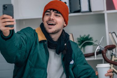 Evde cep telefonlu genç adam video çekiyor veya selfie modunda yayın yapıyor