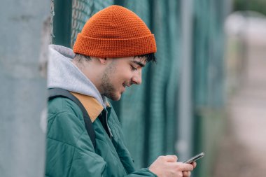 Kışın sokakta cep telefonuyla dolaşan genç bir adam.