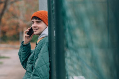 Kışın sokakta cep telefonu ya da cep telefonuyla konuşan genç adam.