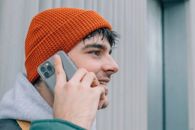 Cep telefonuyla konuşan şapkalı genç adamın portresi.