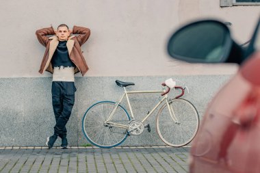 Şehir arka planında bisikleti olan şık bir genç adam.