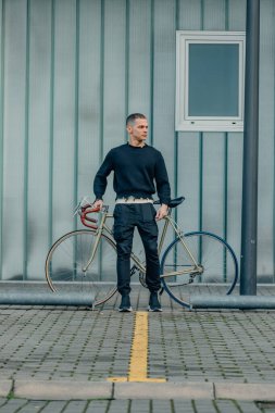 Sokak duvarı arka planı ve kopyalama alanı olan bisikletli genç bir adam.