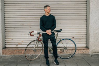 Sokaktaki profiline bakan bisikletli genç adamın portresi.