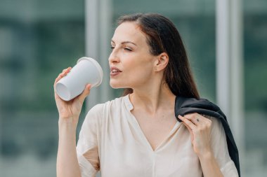 İş kadını ya da işçi dışarıda bardakla içki içiyor.