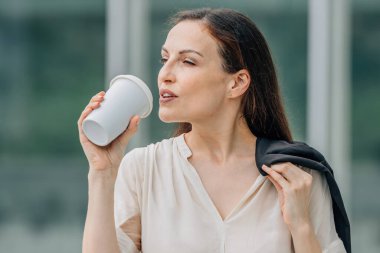 İş kadını ya da işçi dışarıda bardakla içki içiyor.