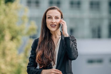İş kadını dışarıda cep telefonuyla konuşuyor.