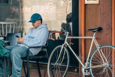 Antika bisikletli genç adam terasta kahve içiyor.