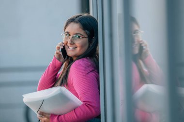 Öğrenci sokakta cep telefonuyla konuşuyor.