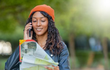 Haritayla seyahat eden genç bir kadın cep telefonuyla konuşuyor.