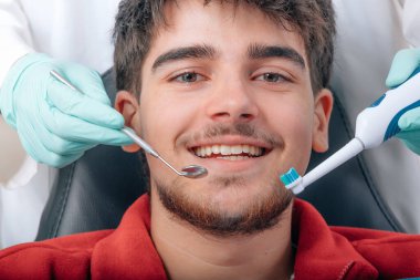 Genç adam diş hekiminde ya da klinikte gülümsüyor