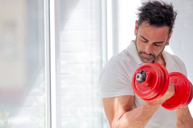 Dambılı adam bisepsi kıvırıyor.