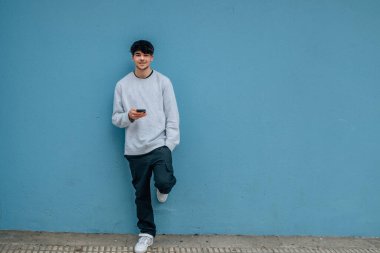 Sokak duvarında cep telefonu ve fotokopi alanı olan genç adam.