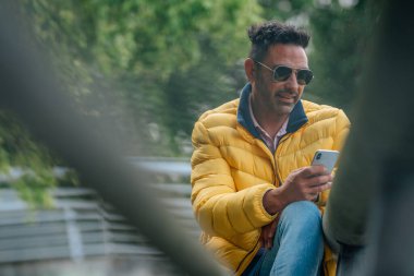 Sokaktaki adam cep telefonunu kontrol ediyor.