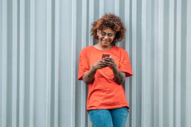 african american girl with mobile phone on street wall 