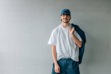 Sokak duvarında şapkası olan genç adam.