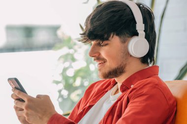 young man with headphones and mobile phone at home