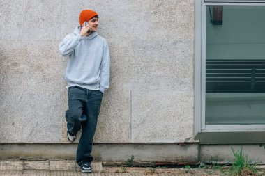 Şık şehirli genç adam sokakta cep telefonuyla konuşuyor.