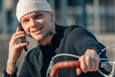 Bisikletli ve cep telefonlu genç adam.