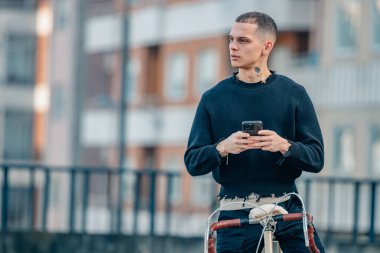 Sokakta bisikletin üstünde cep telefonu olan şehir genci.