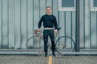 Sokak duvarı arka planı ve kopyalama alanı olan bisikletli genç bir adam.