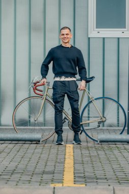 Sokak duvarı arka planı ve kopyalama alanı olan bisikletli genç bir adam.