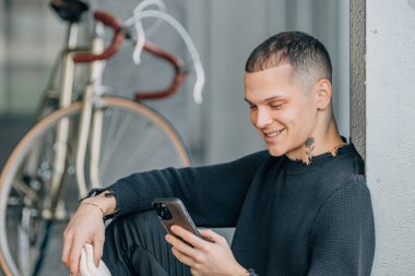 Bisikletli genç adam cep telefonuna bakıyor.
