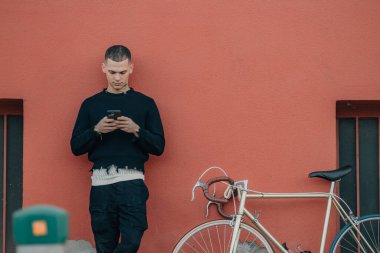 Sokakta cep telefonu olan bisikletli genç bir adam.