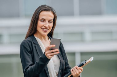 yönetici ya da iş kadını cep telefonuyla dışarıda