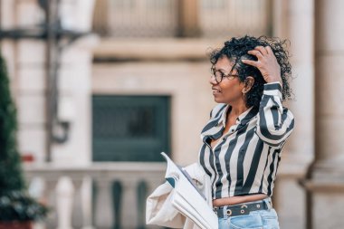 Afro-Amerikan Latin kadın şehir sokaklarında seyahat haritası taşıyor.