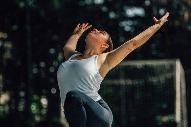 Genç kadın antrenman yapıyor ya da dışarıda spor yapıyor.