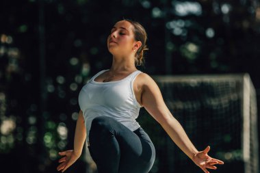 Genç kadın antrenman yapıyor ya da dışarıda spor yapıyor.