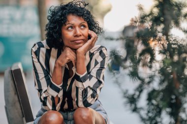 Stresli bir ifadeyle sokakta oturan bir kadın.