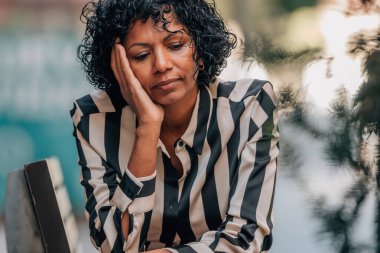 Stresli bir ifadeyle sokakta oturan bir kadın.