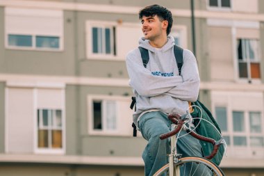 Genç bir adam ya da öğrenci klasik bisiklete biniyor.