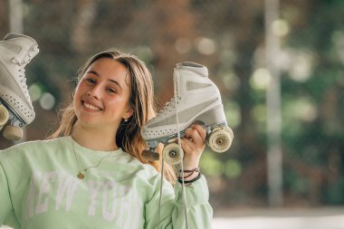 Patenleriyle dışarıda gülümseyen artistik patinaj sporcusu