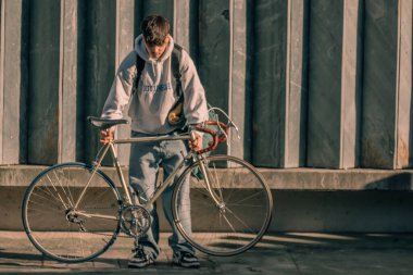 Sokaktaki genç adam, duvarında kopyalanmış eski bir bisikletle