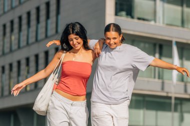 İki arkadaş sokakta kahkahalarla gülüyor.