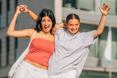 İki arkadaş sokakta kahkahalarla gülüyor.