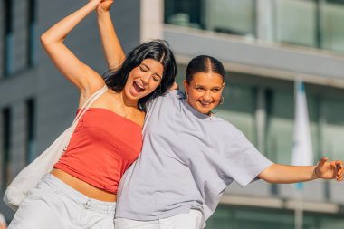 İki arkadaş sokakta kahkahalarla gülüyor.