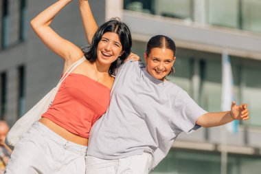 İki arkadaş sokakta kahkahalarla gülüyor.