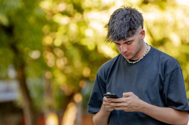 Genç adam cep telefonuna ya da akıllı telefonuna bakıyor.