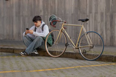 Cep telefonu ve klasik bisikleti olan genç bir adamın şehir manzarası