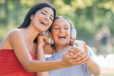 Sokakta eğlenen iki arkadaş cep telefonuna bakarak kahkaha atıyor.