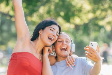 Sokakta eğlenen iki arkadaş cep telefonuna bakarak kahkaha atıyor.